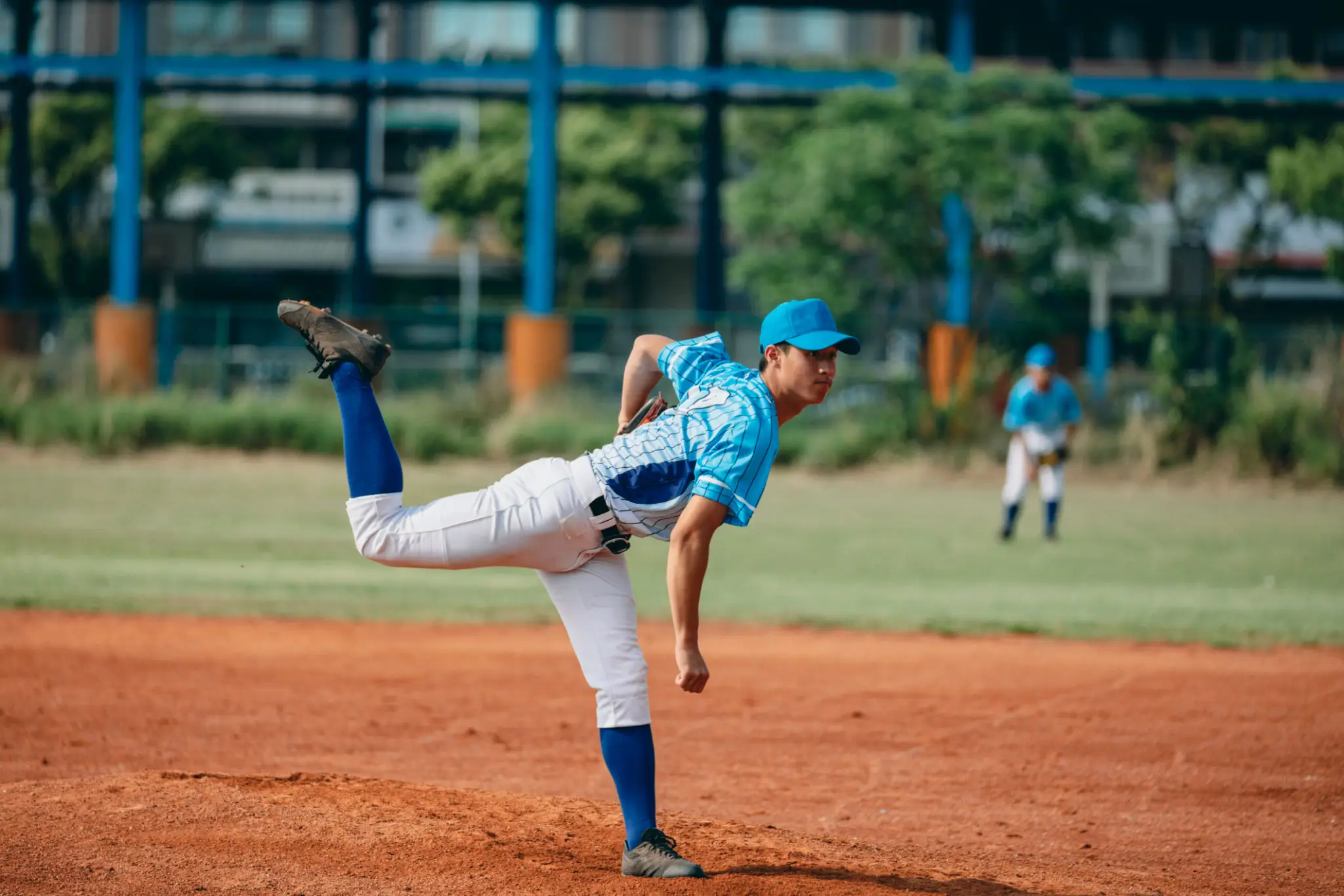 Baseball pitcher in blue uniform mid-pitch